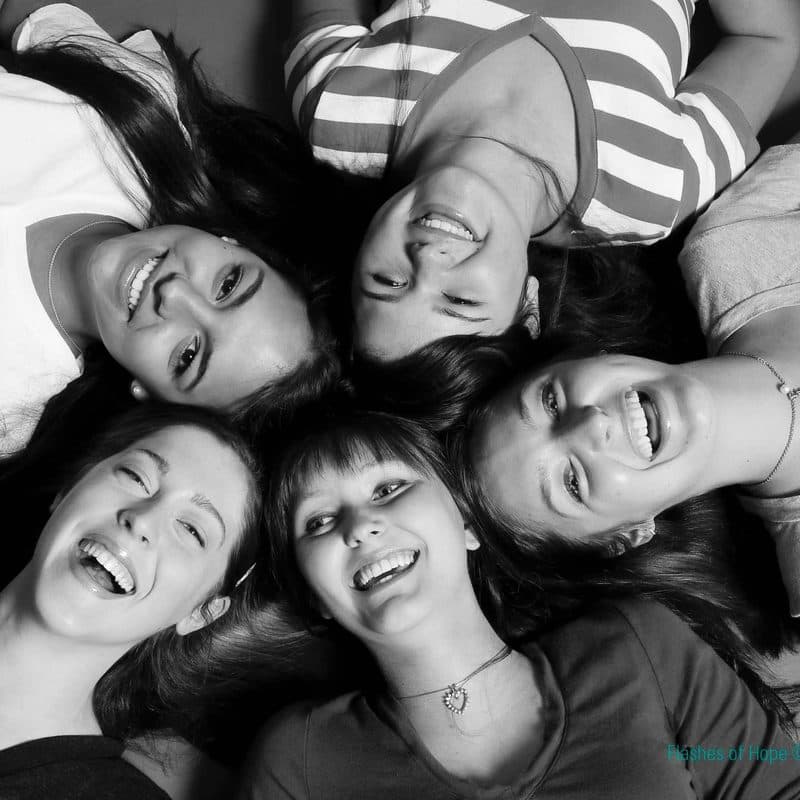 Friends lying with their heads together in a circle, laughing